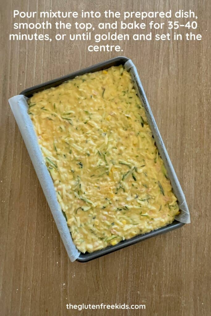 Zucchini slice mixture spread evenly in a lined baking dish before baking
