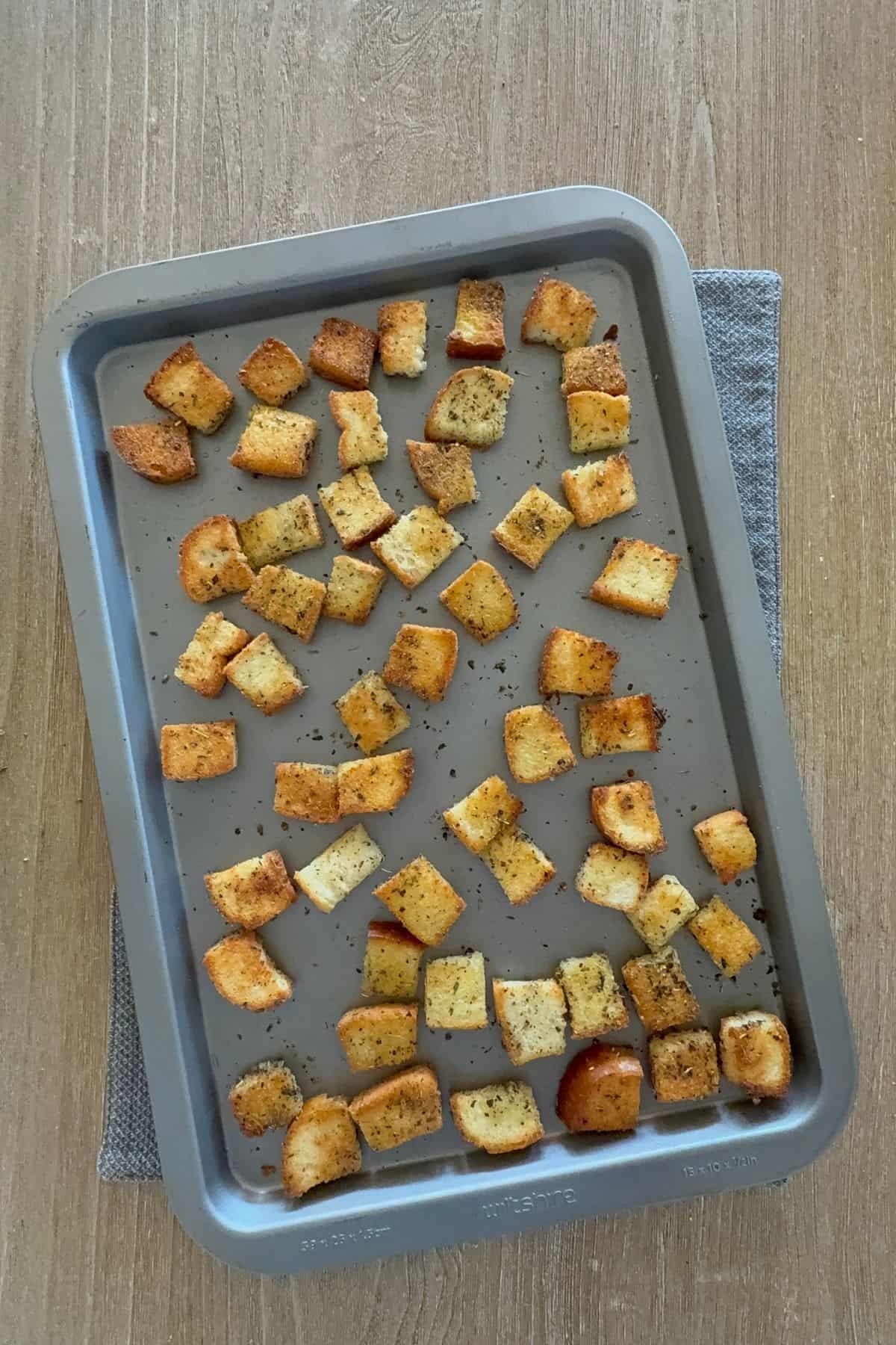 Freshly baked gluten-free croutons golden on a parchment-lined baking tray
