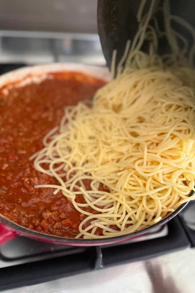 cooked gluten free spaghetti added to bolognese sauce